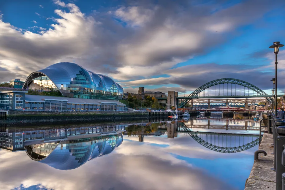 El Sage y el puente Tyne reflejados en el río al atardecer en Newcastle